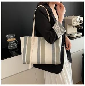 Detail of canvas tote bag with vertical stripes and slim leather straps for women