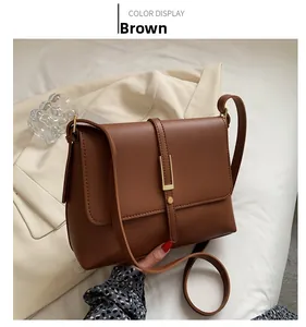 Detail view of a vintage brown leather shoulder bag with gold clasp and smooth texture