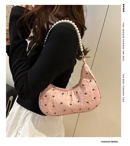 Close-up of pink pleated shoulder bag with bow pattern and pearl strap detail