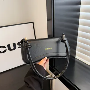 Minimalist black leather crescent hobo bag with gold hardware and unique knot strap detail