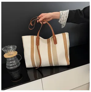 Detailed close-up of a striped tote bag featuring vertical brown patterns and leather handles