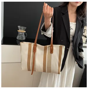 Detailed view of the large canvas tote bag with vertical stripes and leather straps