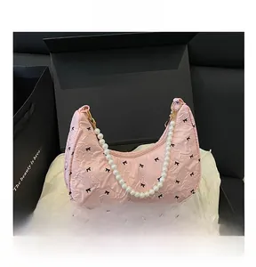 Detailed shot of pink crescent bag with bow patterns and elegant pearl chain handle