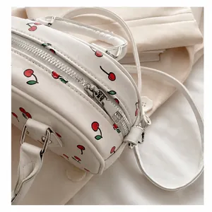 Detail of smooth silver zipper and red cherry print on white leather handbag