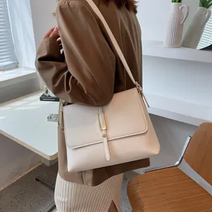 Minimalist cream shoulder bag with gold U-shaped metal buckle and flip cover design