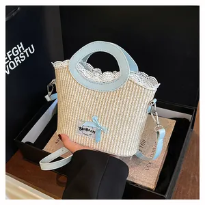 Détail du sac en paille avec bordure en dentelle, nœud bleu et logo dans un coffret cadeau
