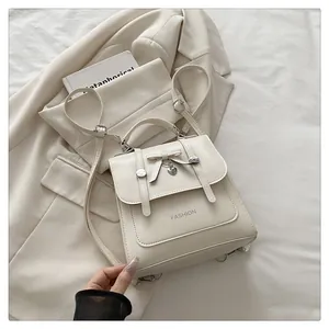 Detail of cream mini backpack with bow decoration and heart-shaped pendant on fabric