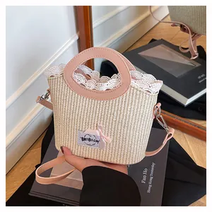 Détail du sac seau en paille d'été avec dentelle blanche, nœud rose et anse en cuir
