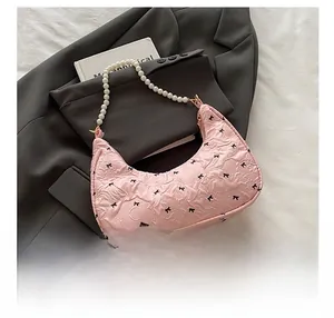 Detail of pink hobo bag with bow patterns and elegant white pearl beaded handle