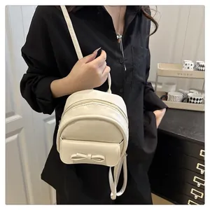 Side view of model wearing a beige mini backpack with a stylish bow decoration