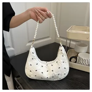 Detail of white jacquard crescent bag with black bow patterns and pearl handle strap