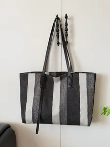 Vertical striped oversized woven tote bag with leather straps and decorative tassel