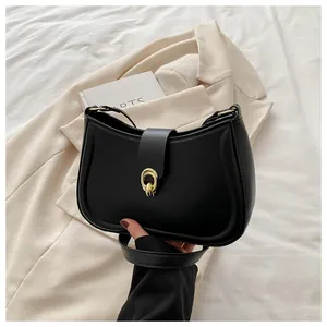 Detail of a black crescent shoulder bag featuring a gold double-ring twist lock