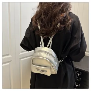 Silver metallic mini backpack with bow detail shown on model for size and style