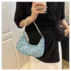 Detail of light blue crescent bag with black bow patterns and elegant white pearl handle