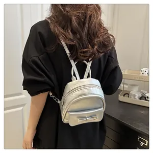 Detailed back view of a silver mini backpack with a bow detail on a fashion model