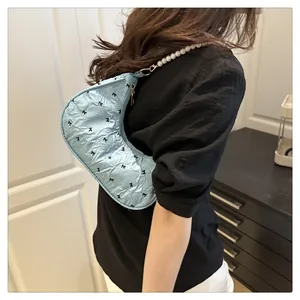 Detail of light blue crescent bag with black bow patterns and pearl shoulder strap