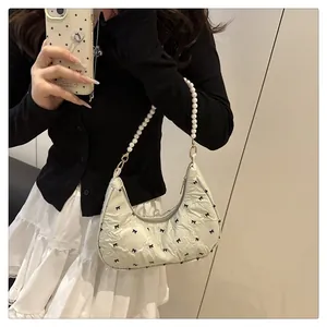 Detail of hobo bag with mini bow prints, quilted texture, and faux pearl handle