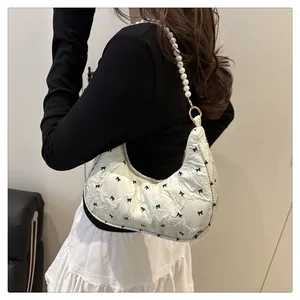 Detail of cream hobo bag with black bows, quilted fabric and pearl shoulder strap