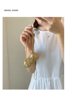 Détail de la pochette de soirée dorée en forme de cacahuète avec strass et chaîne fine