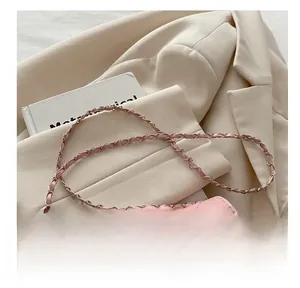 Close-up of pink quilted crossbody bag with silver rotating lock and chain strap