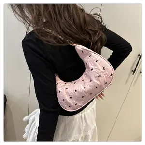 Detail of pink hobo bag with black bow patterns and elegant pearl shoulder strap