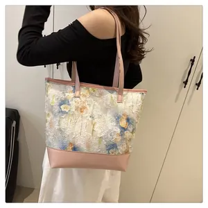Close-up of pink floral jacquard tote bag with leather straps in a bright indoor setting