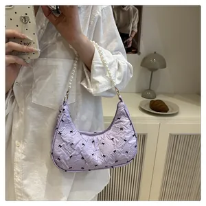 Close-up of lavender crescent handbag with bow patterns and pearl handle detail