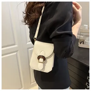 Détail d'un sac bandoulière beige avec une boucle décorative en anneau de bois foncé