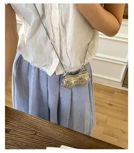 Dettaglio della mini borsa a tracolla a forma di arachide con perle e strass e catena