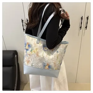 Detail of floral texture fabric and light blue leather strap on large tote bag