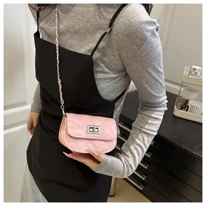 Close-up of pink quilted mini bag with silver twist lock and chain strap on shoulder
