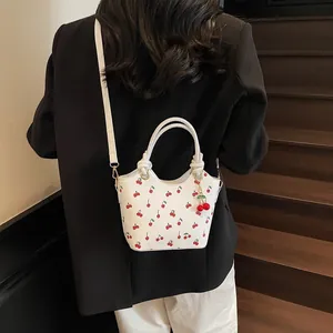 Sac seau blanc rétro avec imprimé cerise et breloque sur un blazer noir