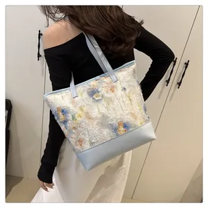 Detail of floral embroidery on a large tote bag with light blue leather handles