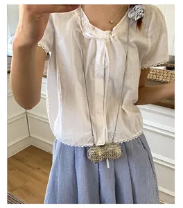 Mini sac à chaîne argenté en forme de cacahuète avec strass porté par un modèle