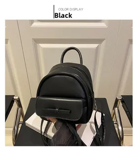 Detail of black mini backpack with a delicate bow on the front pocket and PU leather finish