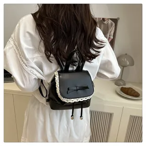 Détail d'un mini sac à dos en cuir noir avec bordure en dentelle et nœud pour femme