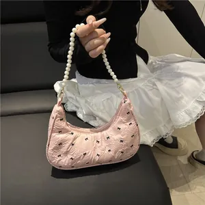 Pink pleated saddle bag with black bow prints and a white pearl chain handle