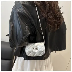 Detail of silver quilted crossbody bag with metal twist lock and chain strap