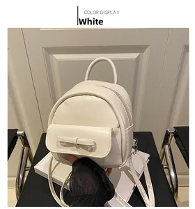 Close-up of a white mini leather backpack featuring a stylish bow pocket and silver hardware