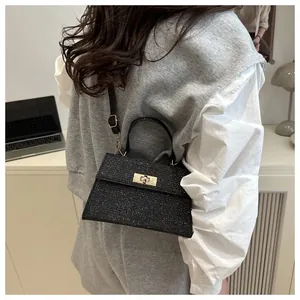 Nahaufnahme der schwarzen Glitzer-Handtasche mit goldener Drehsperre und festem Griff