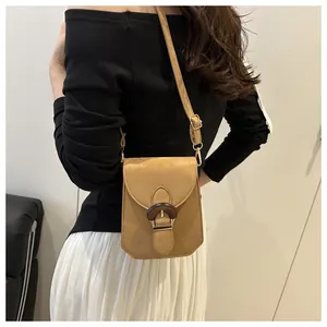 Gros plan d'un sac bandoulière kaki vintage avec boucle en bois porté à l'épaule