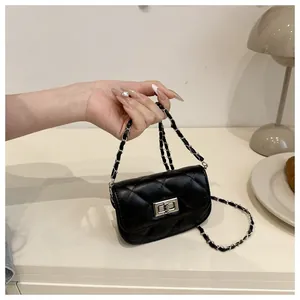 Detail of black quilted mini bag with silver rotating lock and chain strap