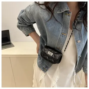 Detail of black quilted leather mini bag with silver twist lock and metal chain strap