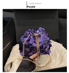 Detail of purple sequin bucket bag with gold chain strap and white pearl accents