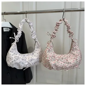 Détail de sacs demi-lune floraux avec poignées froncées et décorations de nœuds élégants