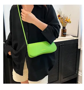 Détail du sac bandoulière vert néon en cuir grainé avec rabat ondulé et logo doré