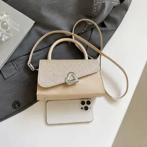Close-up of beige sequin handbag with heart buckle and phone for size comparison