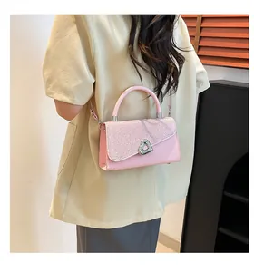Detailed view of pink sequined square bag with silver heart-shaped clasp and top handle