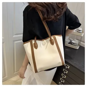 Lifestyle shot of an elegant cream and brown tote bag worn over the shoulder in a minimalist room